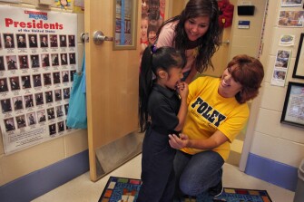 Lucy Cunningham, right, an ESL paraeducator at Foley Elementary, helps kindergartner Lizabeth Guerra try on pants to replace the oversized pair she wore to school while volunteer Dora Gutierrez looks on. Foley’s staff collects food and clothing for needy families, teaches adult ESL classes, and helps families translate documents.