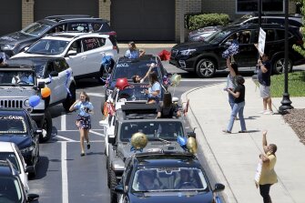 Graduates wave from their cars while participating in a senior graduation car parade on Friday, May 1, 2020, at Academy of the Holy Names in Tampa, Fla.