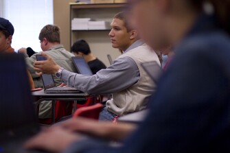 Mr. Davis works on a computer while working on a history project with his classmates.
