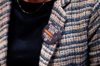 An attendee wears a "Screens Down, Pencils Up," button during a school board meeting at the Lower Merion School District Administration Building on May 11, 2026, in Ardmore, Pa.