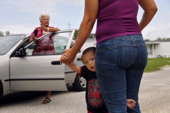 Darien Zelaya, 2, clings to his mother Delkin Carcamo while she speaks with ESL parent liaison Ida White outside their trailer in Foley, Ala. Ms. White works closely with the Spanish-speaking families who live in the southern half of the 28,000-student Baldwin County school system, where Foley is located.
