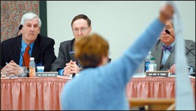 Terry Lux, the principal of Shead High School in Eastport, unfurls more than 10 feet of paper showing the organizational chart of a Florida school district to Maine lawmakers during a hearing on plans to overhaul the state's school administrative structure.
