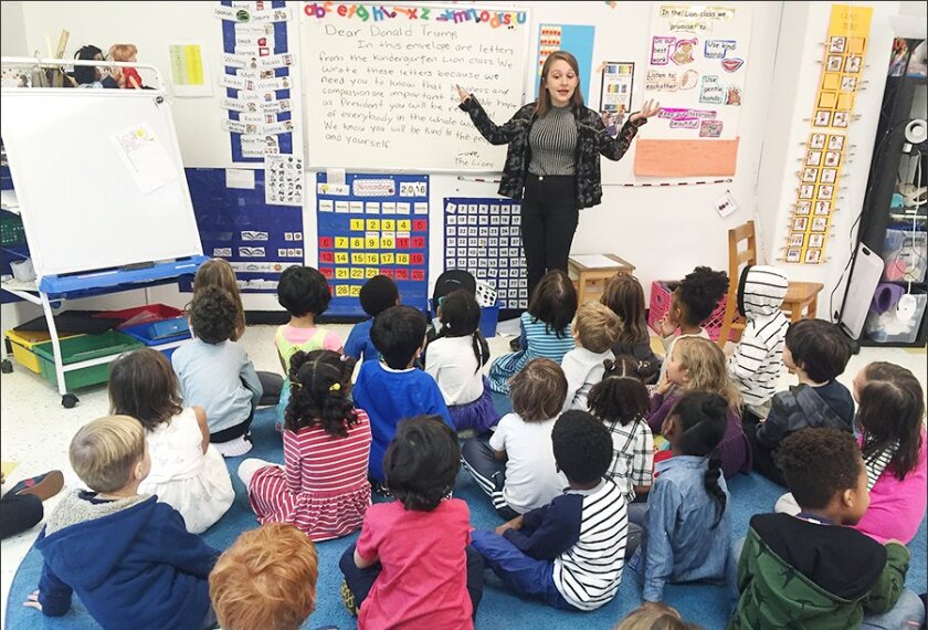 Teacher Emily Silver helps kindergartners at the Co-op School in the Bedford-Stuyvesant community of Brooklyn, draft letters to President-elect Donald Trump. The letters will be mailed to the new President.