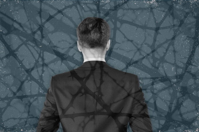 Man in suit, collaged with thorny branches in front and behind him.
