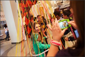 Hazal Ozkan, 12, poses for a photo as she spins around in a chair inside the Hyper Hyperboloid at MoMath. The installation gives the impression of being curved, but its lines are actually straight.